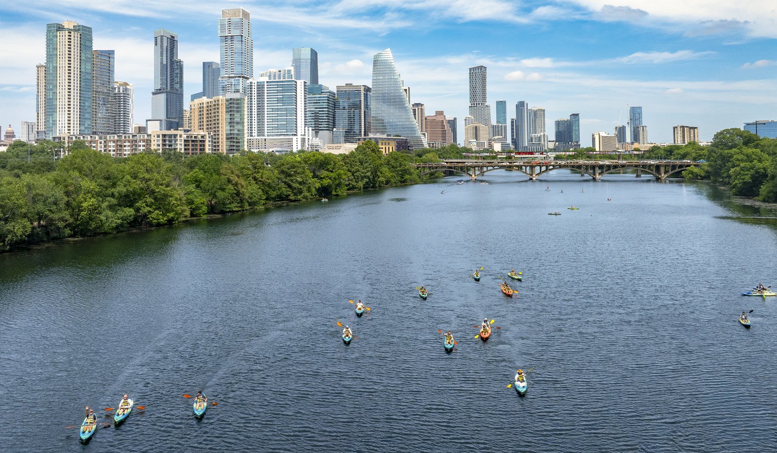 Multiple kayakers on a lake in the city.