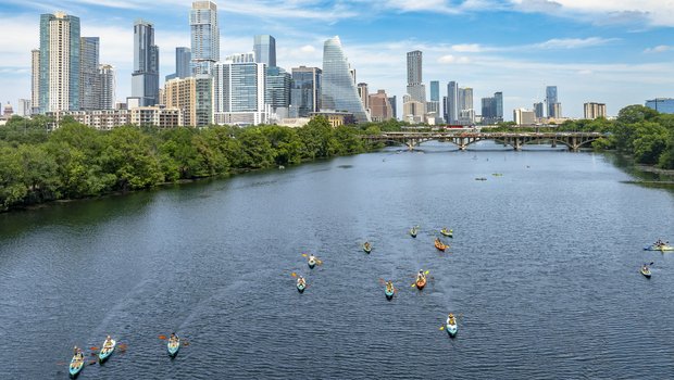 Multiple kayakers on a lake in the city.