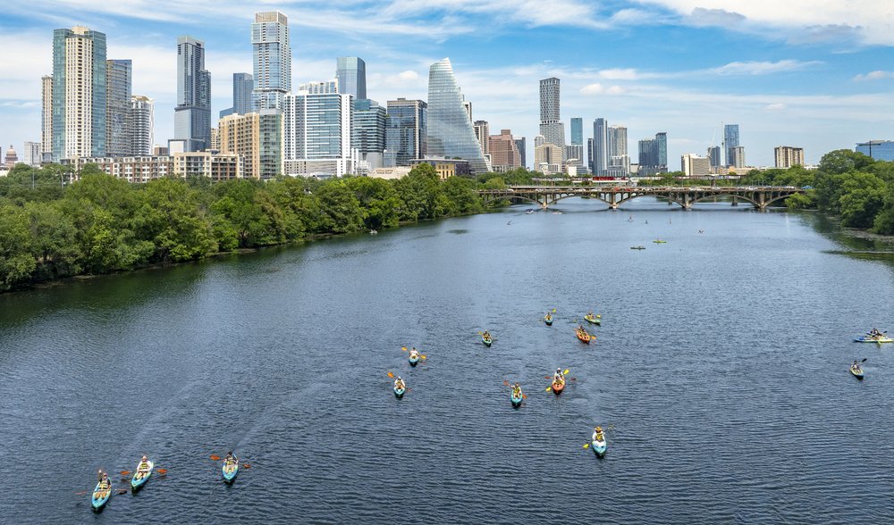 Multiple kayakers on a lake in the city.