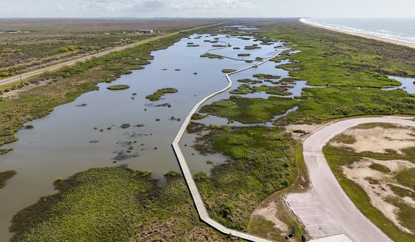 An overhead view of a borad walk running through a marsh.