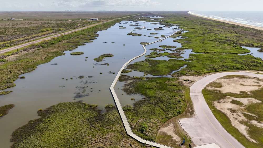 An overhead view of a borad walk running through a marsh.