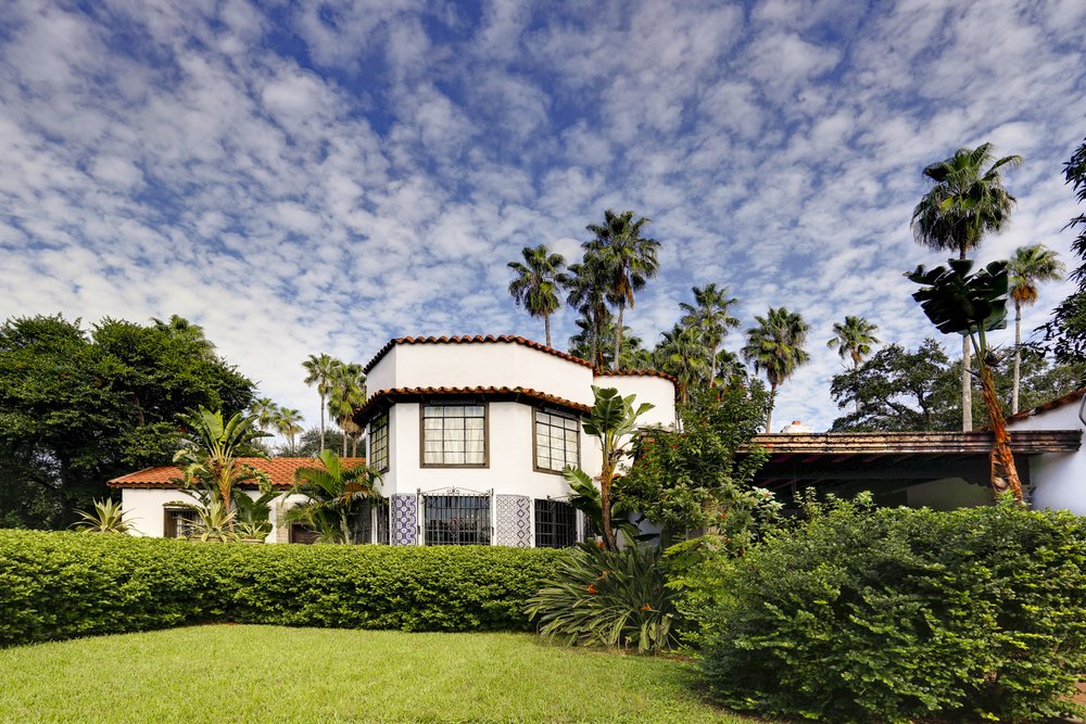 Large home surrounded by bushes and trees.