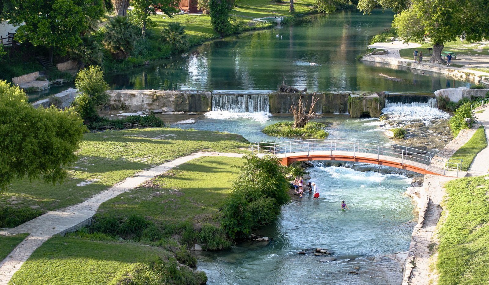 A view of a park with trails, water, and a bridge.