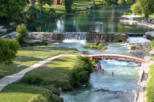 A view of a park with trails, water, and a bridge.