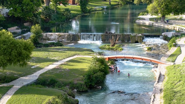 A view of a park with trails, water, and a bridge.