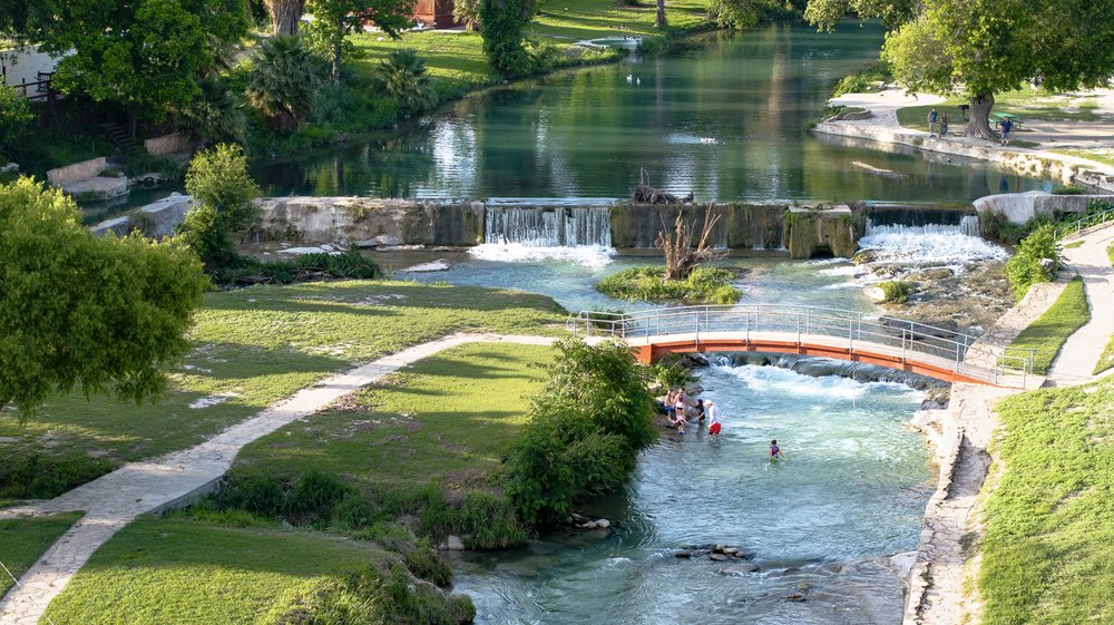 A view of a park with trails, water, and a bridge.