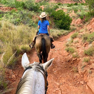 Riders on horseback traverse the red dirt trails at Caprock Canyon state park