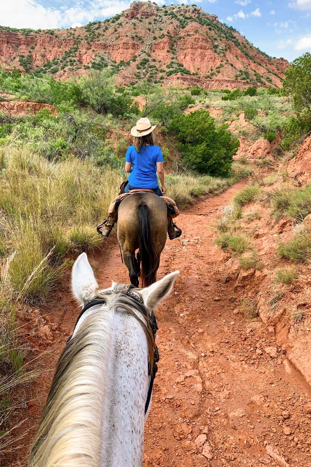Riders on horseback traverse the red dirt trails at Caprock Canyon state park