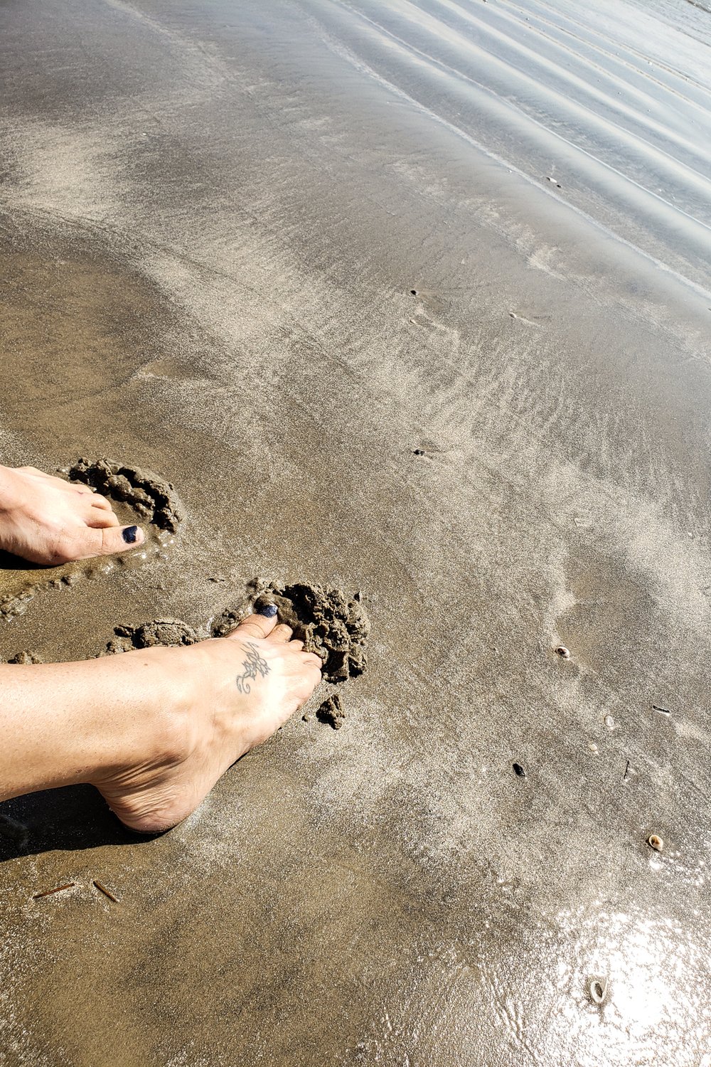 Toes dig into sand along the shore at Sea Rim state park