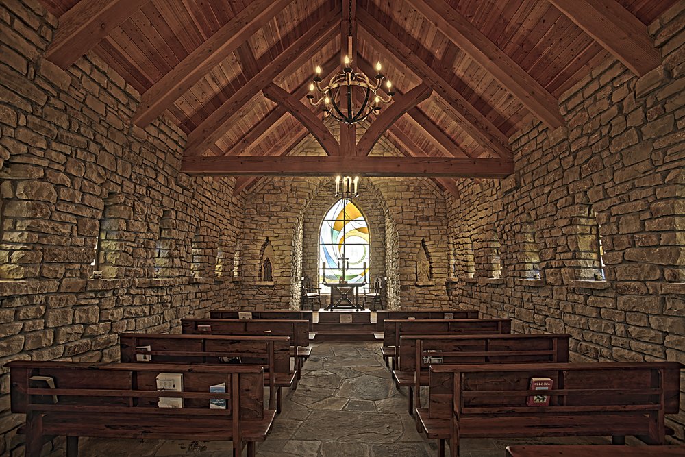 View of a stained glass window behind a podium inside a chapel