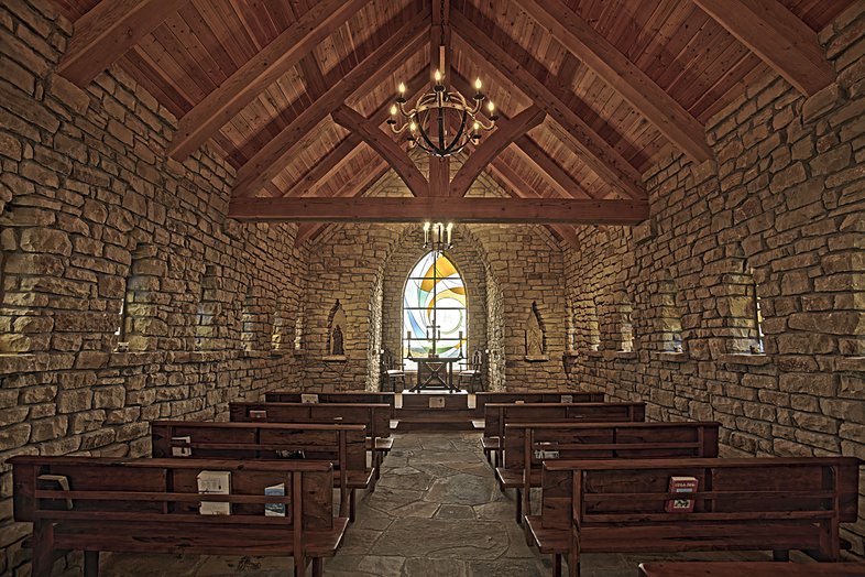 View of a stained glass window behind a podium inside a chapel