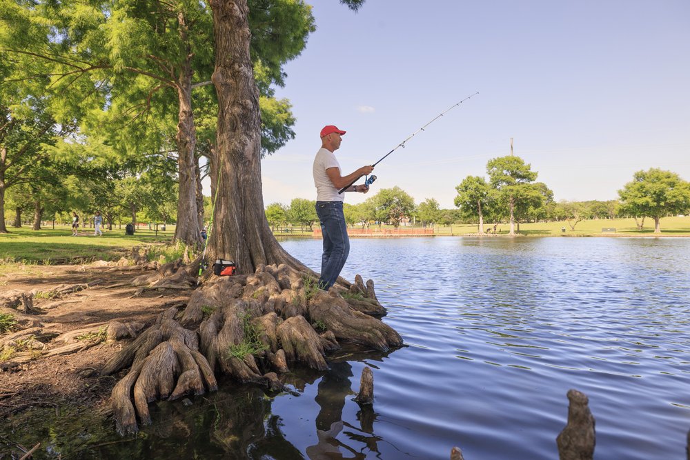 An angler fishes along the shore of Chisolm Park