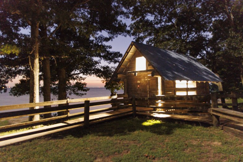At dusk, light shines from within a screened shelter along the shore of Lake Livingston