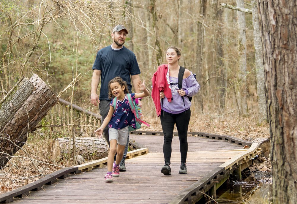 A family walks along the boardwalk on the Pineywoods Boardwalk trail at Lake Livingston State Park
