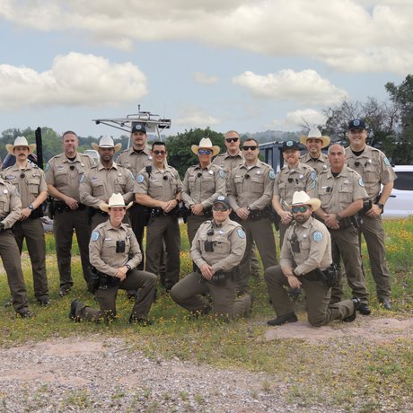 A group of sixteen game wardens pose for a group photo