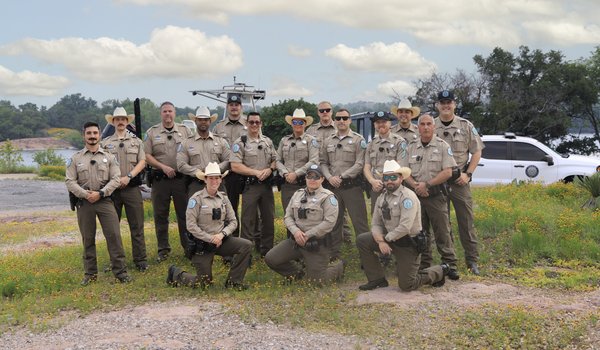 A group of sixteen game wardens pose for a group photo