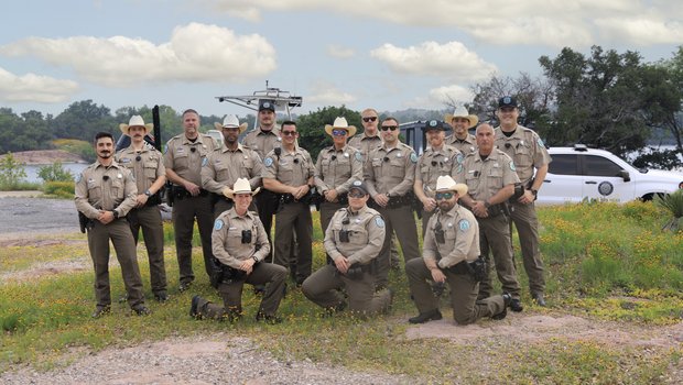A group of sixteen game wardens pose for a group photo