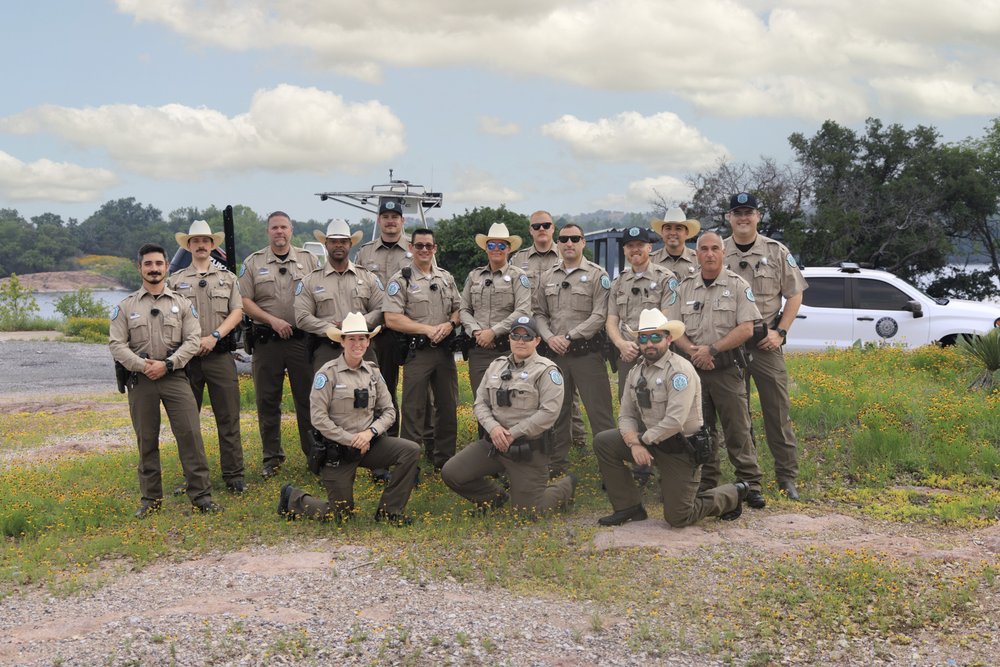 A group of sixteen game wardens pose for a group photo