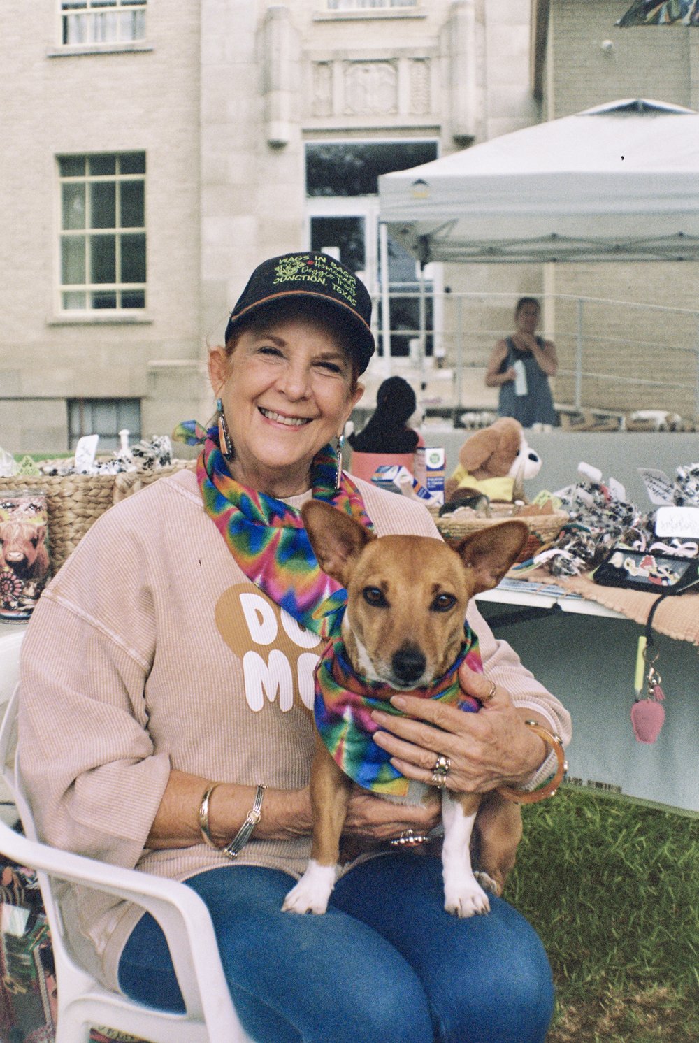 Connie Booth sits in white chair holding her dog on her lap