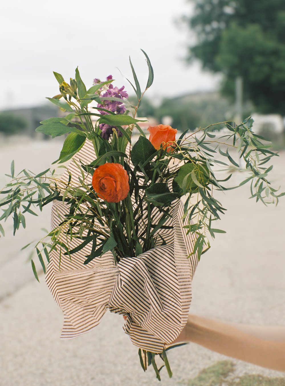 A hand holds a wrapped bouquet of flowers