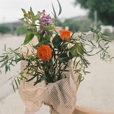 A hand holds a wrapped bouquet of flowers
