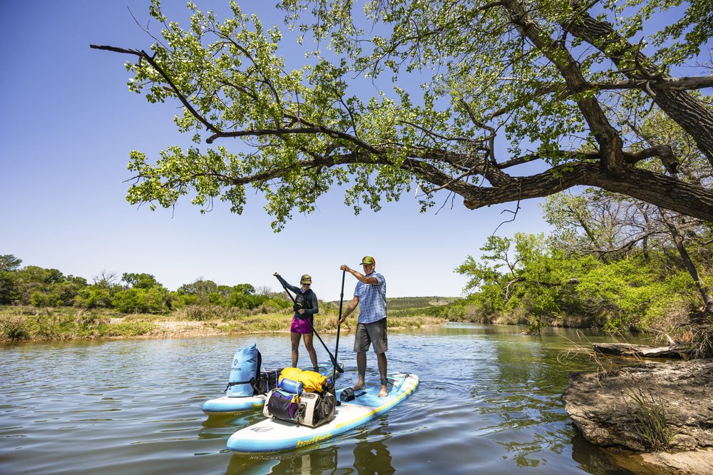 Pair of paddle boards on Brazos River floating under large tree branch
