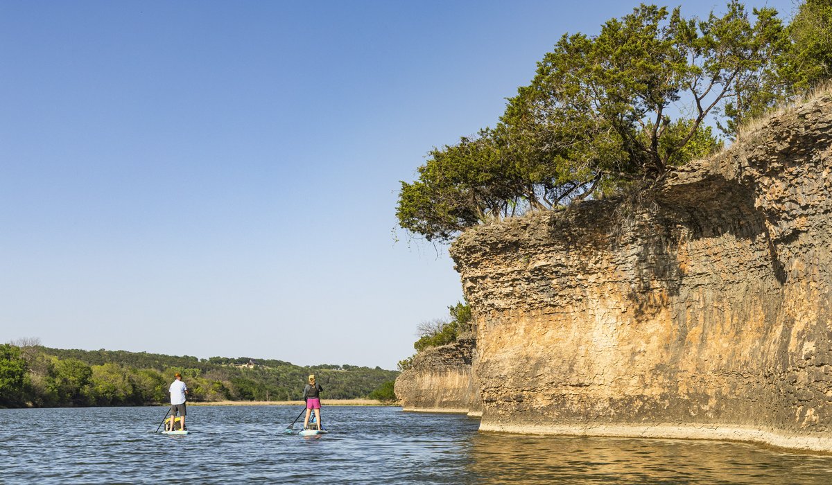 Pair of paddleboarders along a small cliff on the Brazos River