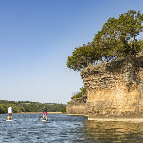 Pair of paddleboarders along a small cliff on the Brazos River