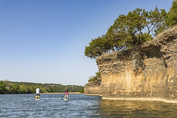 Pair of paddleboarders along a small cliff on the Brazos River