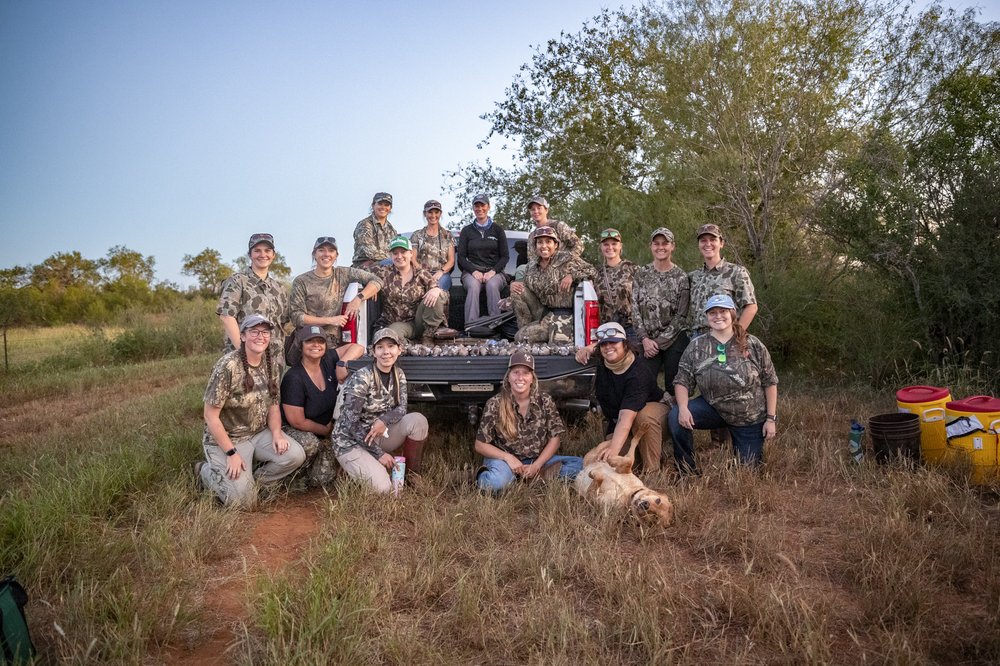 Group of women after a successful dove hunt in a southern Texas field with dog
