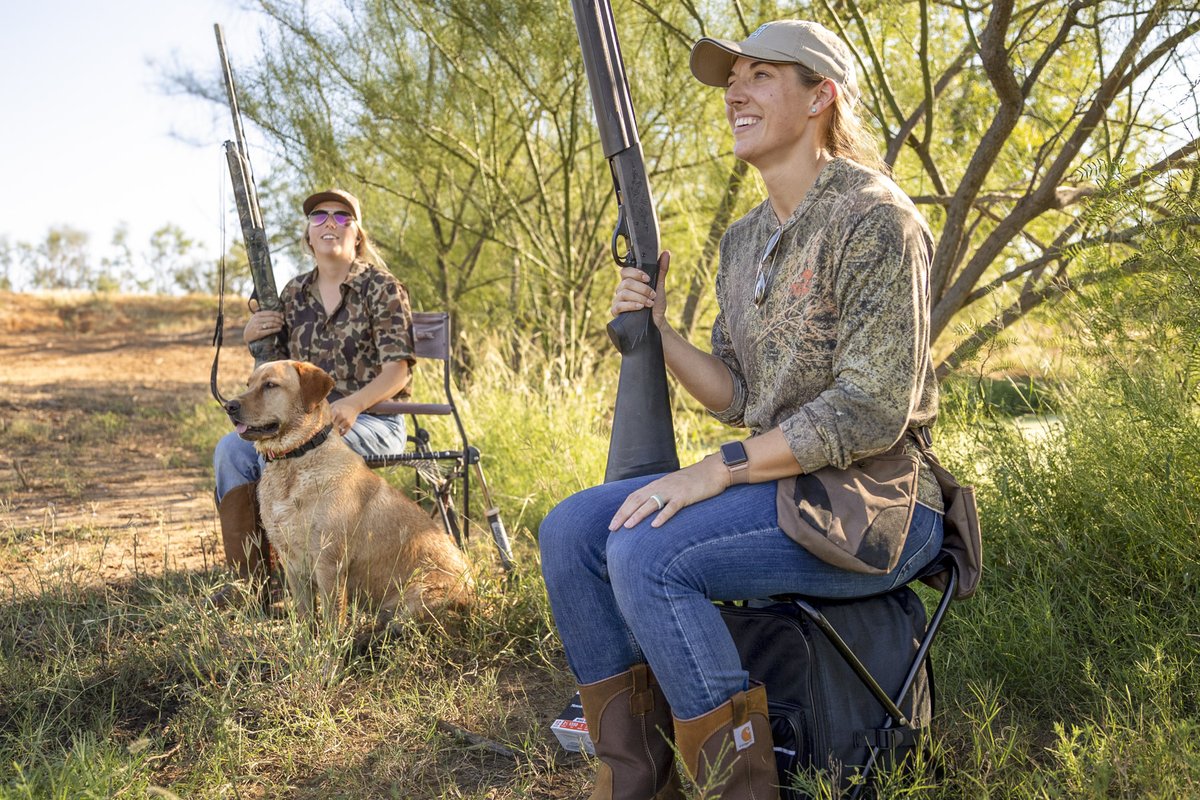 Two women in field in south Texas hunting dove with shotguns and a dog