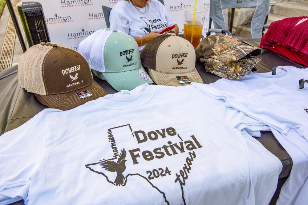 Display of shirts and hats with the Dove Festival logo are laid out on table