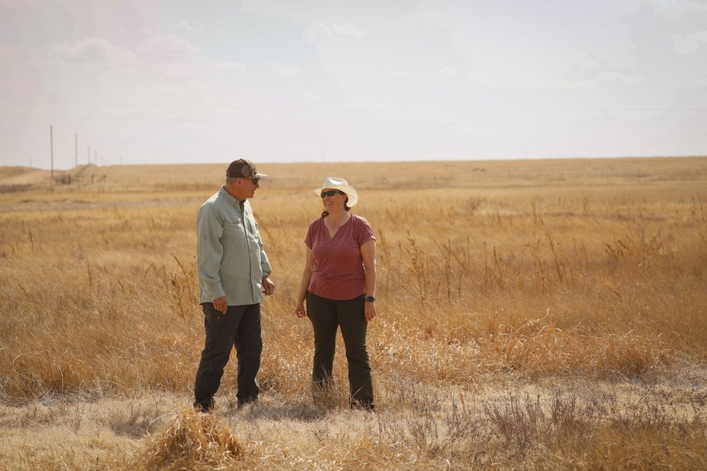 Heather Johnson of TPWD and John Roleyon of Little Las Vegas Ranch standing in a dry field.