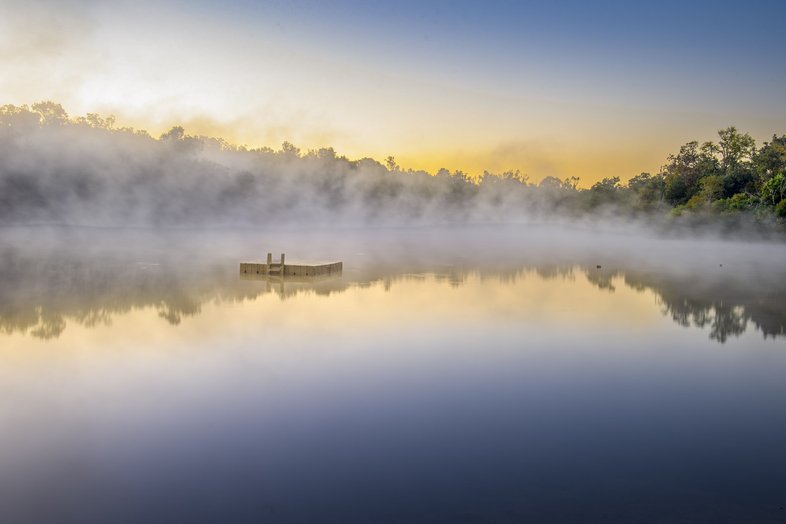 A platform in the middle of a foggy lake.