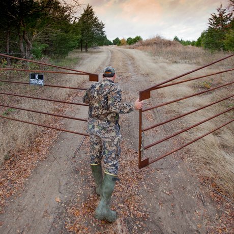 A hunter opens the gate to a leased deer property