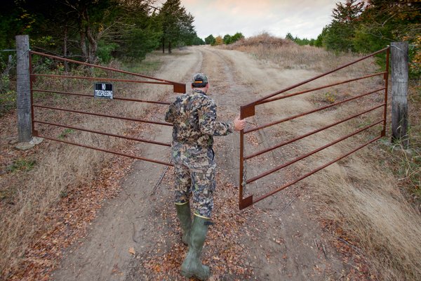A hunter opens the gate to a leased deer property