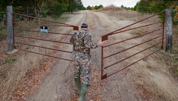 A hunter opens the gate to a leased deer property