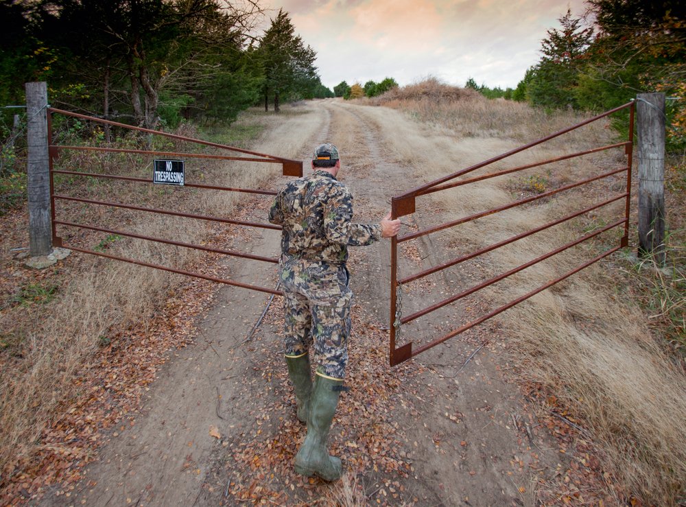 A hunter opens the gate to a leased deer property