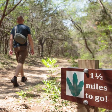 Man hikes by sign showing 1.5 miles to go to dinosaur tracks