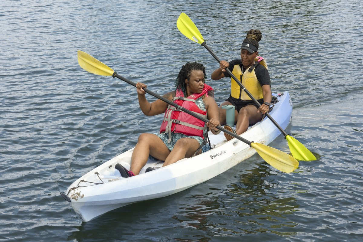 Two women paddle a tandem kayak