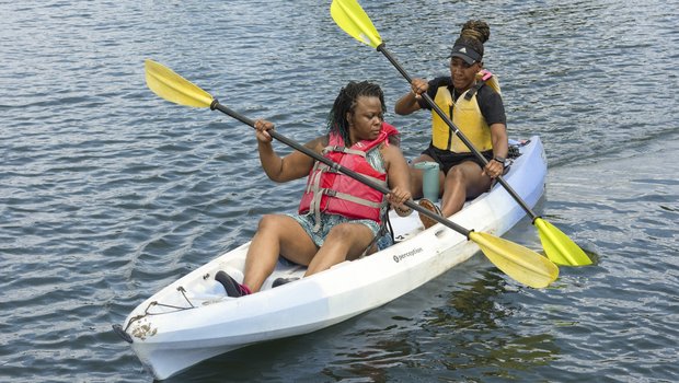 Two women paddle a tandem kayak