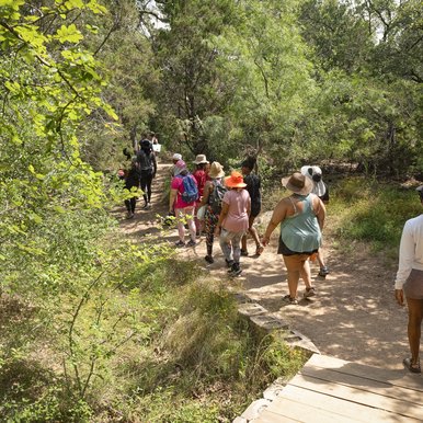 A group of African American women hike along a tree-lined trail