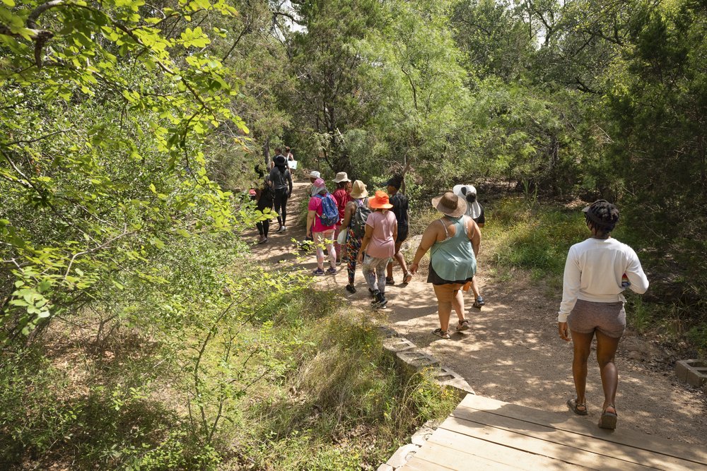 A group of African American women hike along a tree-lined trail