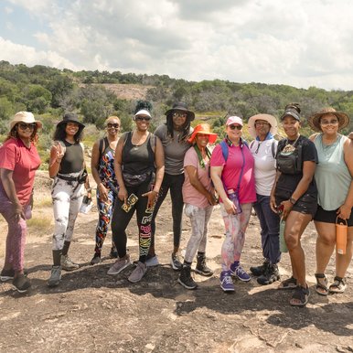 A large group of African American women pose for a photo along a trail