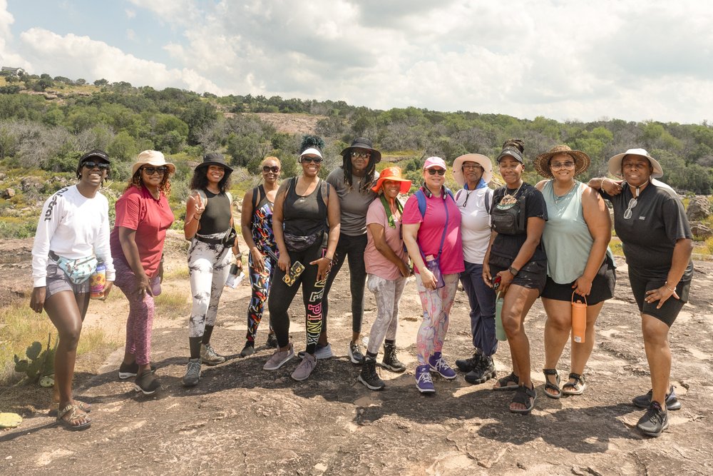 A large group of African American women pose for a photo along a trail