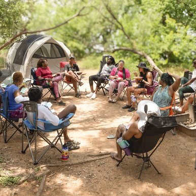 A group of African American women gather around a camp site in the late afternoon