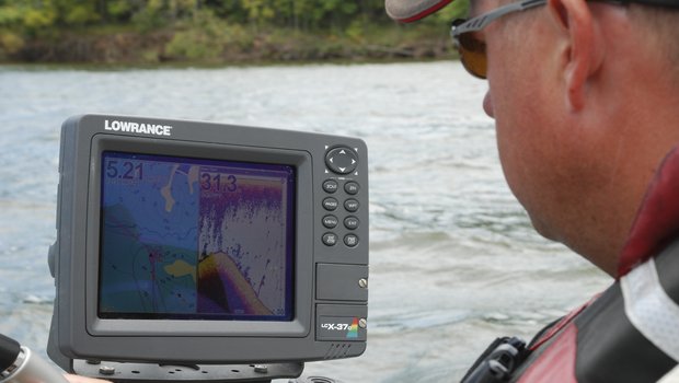 An angler checks the readings on his boat's fish finder screen