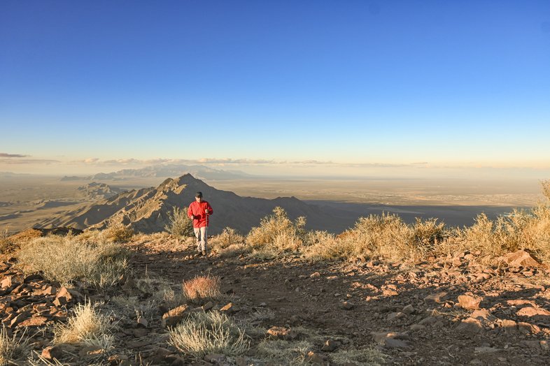 A lone hiker walks along the rocky trail of North Franklin Peak with Franklin Mountains State Park