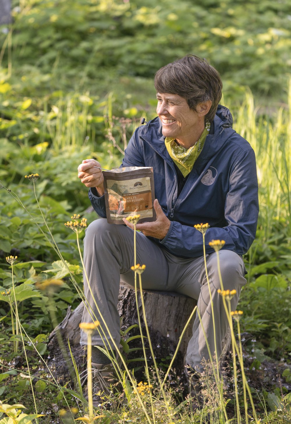 Writer Pam Leblanc sits on a rock and eats from a freeze-dried meal pouch