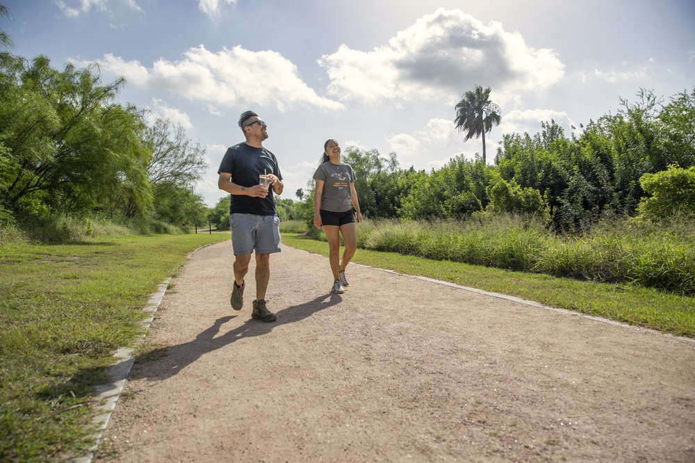 Man and woman walking on dirt trail part of the Caracara Trails in Rio Grande Valley